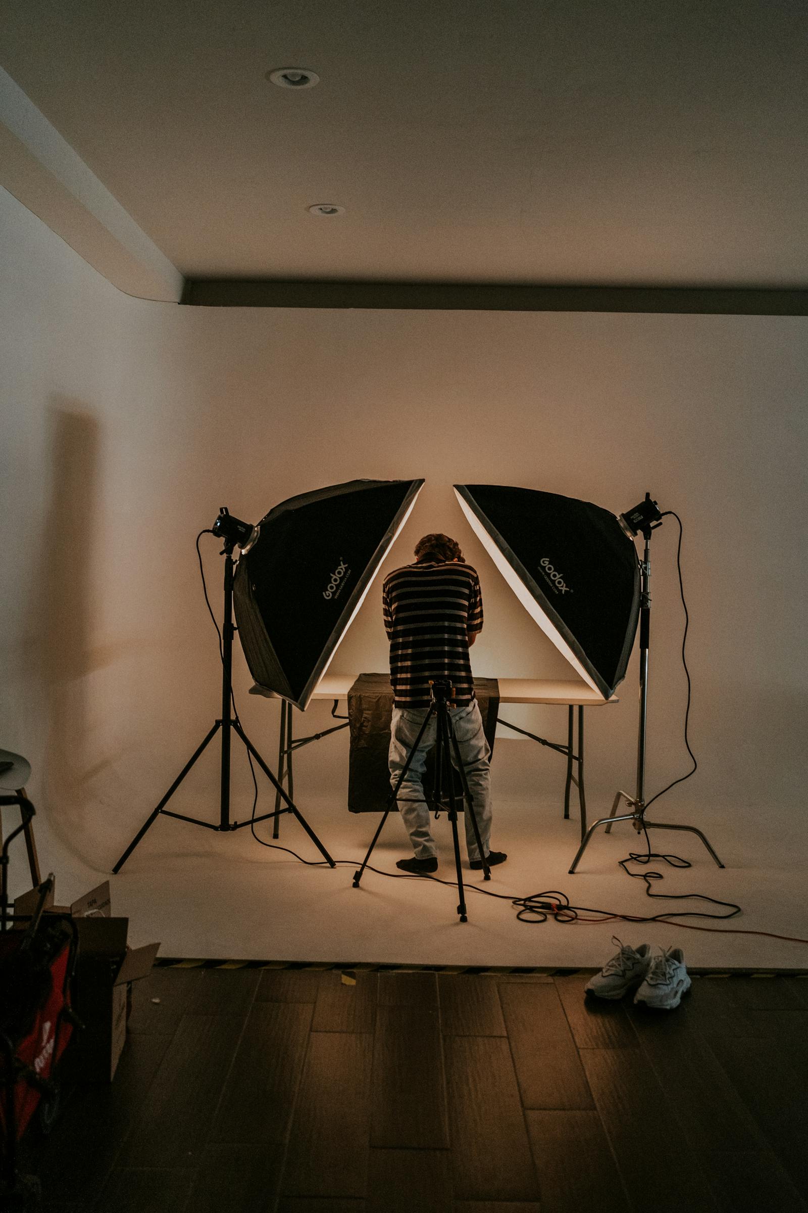 A single Profoto strobe firing through a 4×6 silk on a NIGERIA rooftop at golden hour, two stylists holding the frame against the wind.